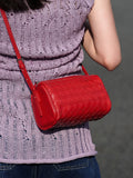 Red lambskin woven leather mini crossbody bag worn over a purple knit top