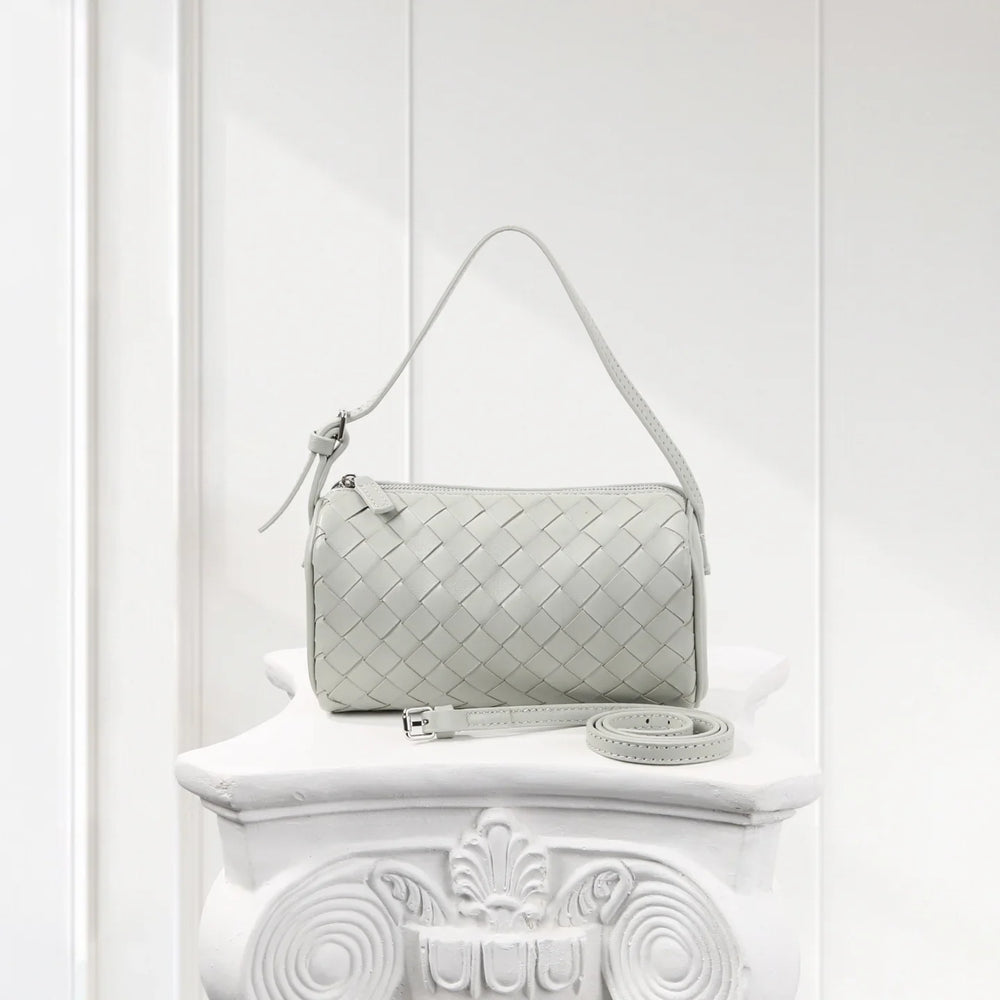 Mini woven lambskin leather handbag with detachable strap on white decorative pedestal