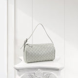Mini woven lambskin leather shoulder bag with top handle on white decorative pedestal