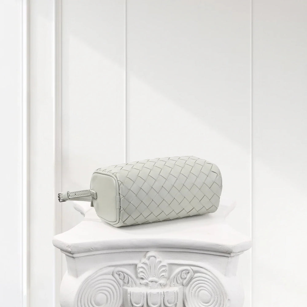 Mini woven lambskin leather Boston bag in light grey on a white ornate pedestal