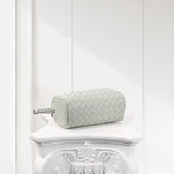 Mini woven lambskin leather Boston bag in light grey on a white ornate pedestal