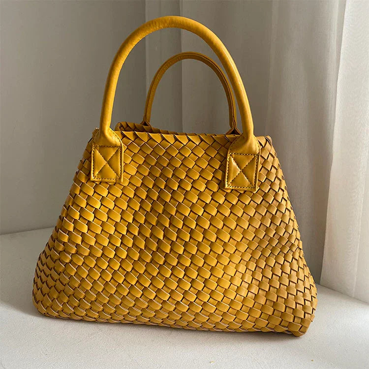 Large handwoven vegan leather tote bag in yellow with double handles, displayed indoors.