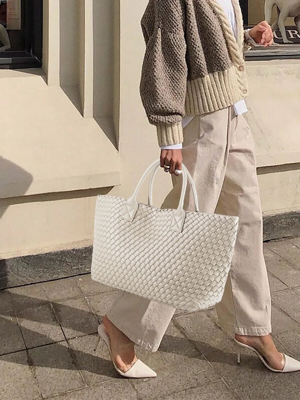 Woman carrying large handwoven vegan leather white tote bag, chic street style