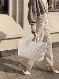 Woman carrying large handwoven vegan leather white tote bag, chic street style