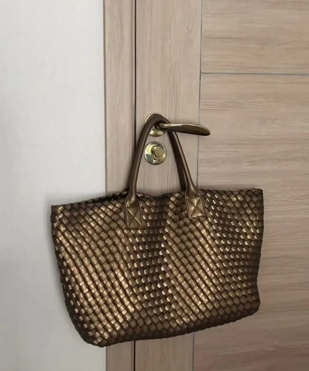 Large handwoven vegan leather tote bag in onyx with dual handles hanging on a door