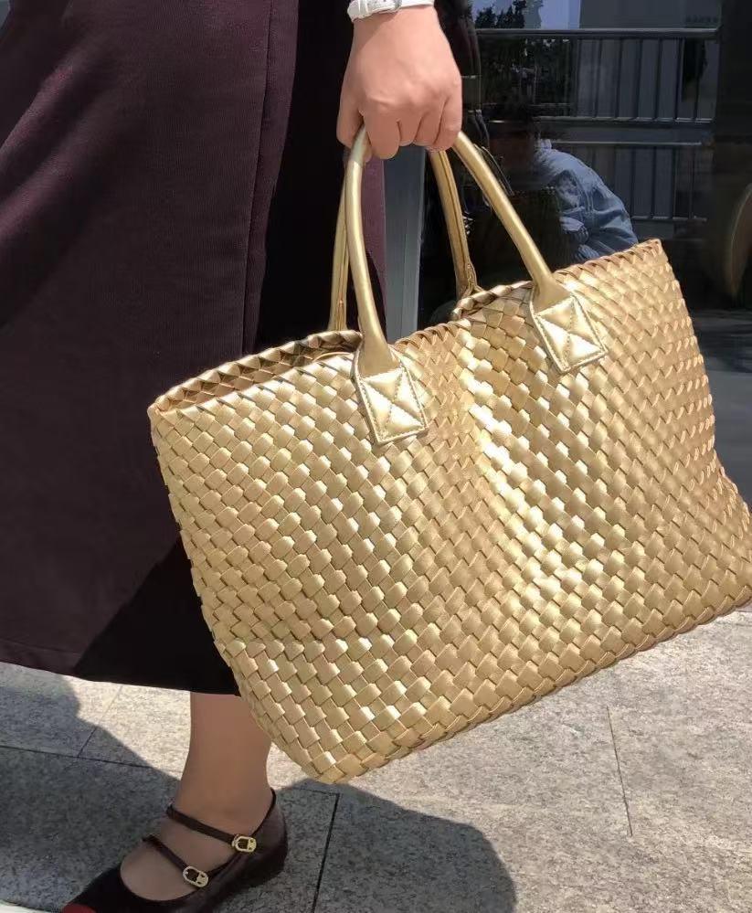 Handwoven gold vegan leather tote bag with double handles carried outdoors