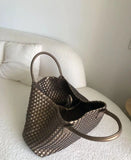 Large handwoven vegan leather tote bag with double handles on a white couch