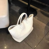 Large handwoven white vegan leather tote bag with double handles on a marble floor