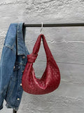 Red lambskin leather knotted handbag with intrecciato weave, hanging beside denim jacket