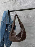 Brown woven lambskin leather knotted handbag hanging beside denim jacket on rack