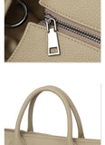 Close-up of beige cowhide leather tote bag with textured finish, silver zipper, and sturdy handles.