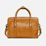 Tan leather Boston bag with top handles and detachable shoulder strap on white background