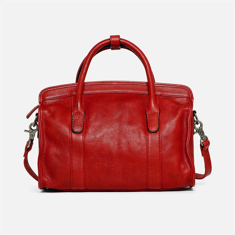 Red leather Boston bag with top handles and detachable shoulder strap on white background
