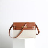 Minimalist leather and canvas crossbody bag with brown flap, gold hardware, and shoulder strap.