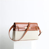 Minimalist leather and canvas crossbody bag with brown flap, gold clasp, and shoulder strap