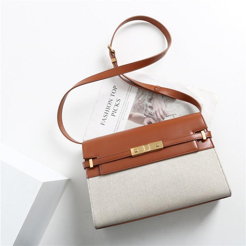 Minimalist leather and canvas crossbody bag with gold hardware on white background