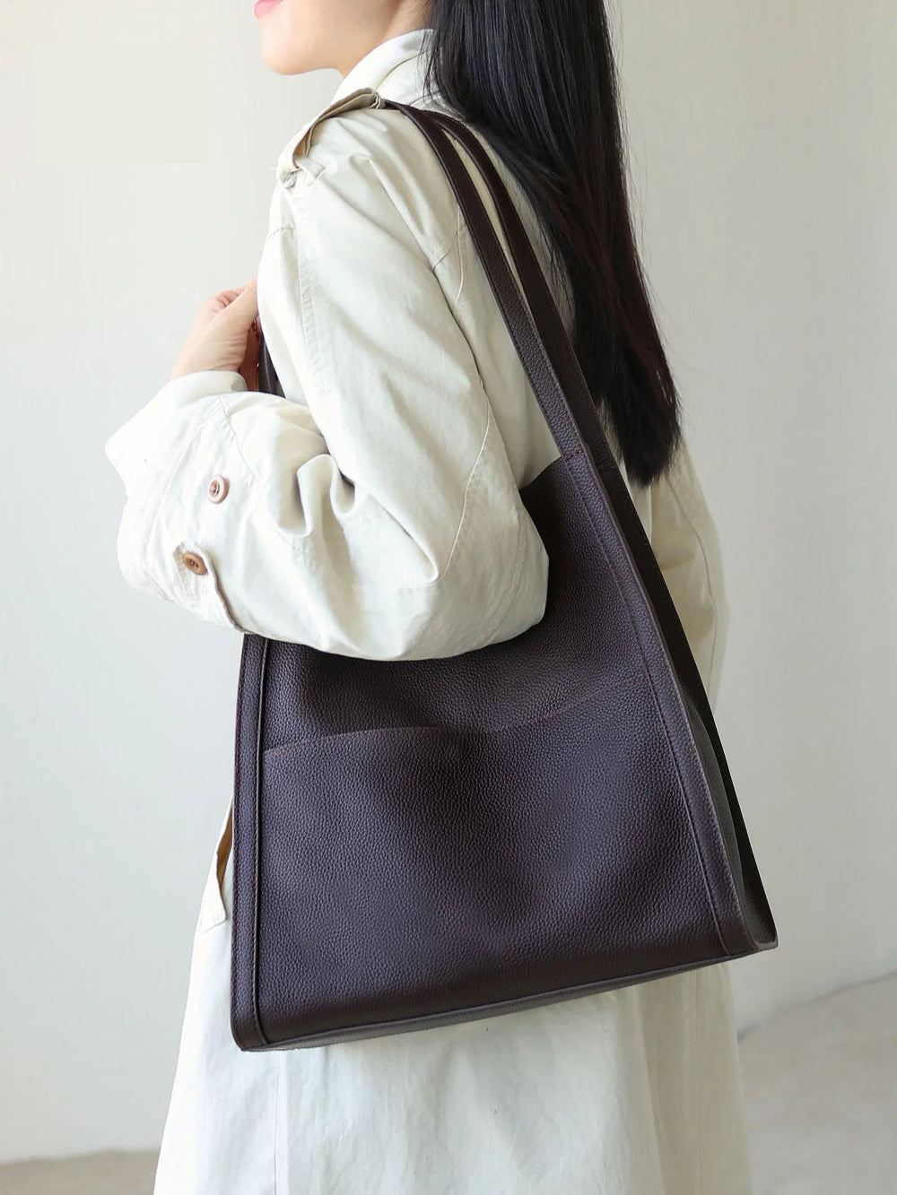 Woman wearing a minimalist brown grain cowhide leather tote bag on shoulder