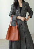 Woman in grey blazer carrying a brown grain cowhide leather tote bag on shoulder