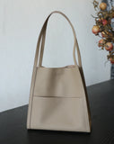 Beige grain cowhide leather tote bag with minimalist design on dark wooden table