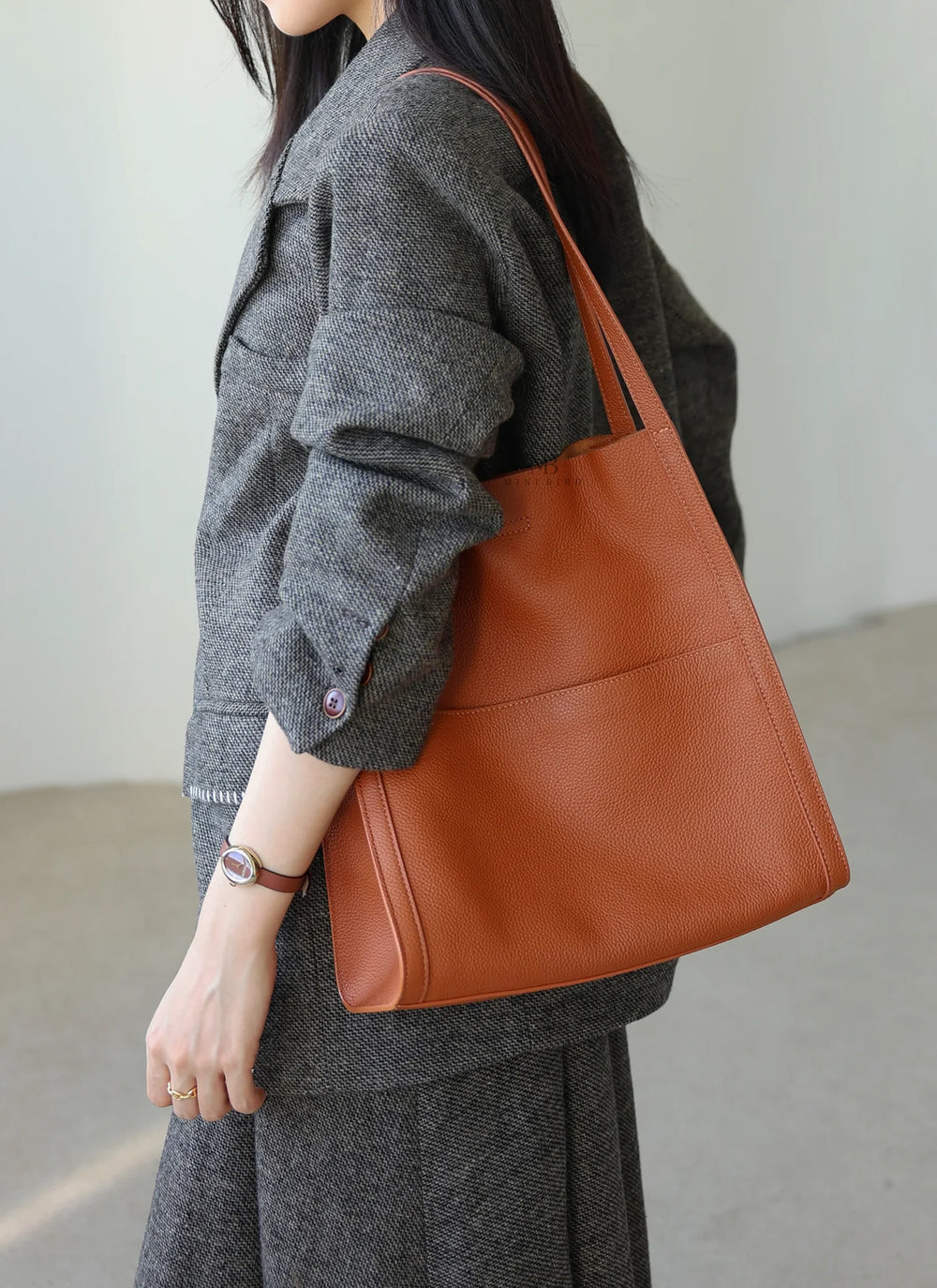 Woman carrying a brown grain cowhide leather tote bag with shoulder straps