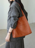 Woman carrying a brown grain cowhide leather tote bag with shoulder straps