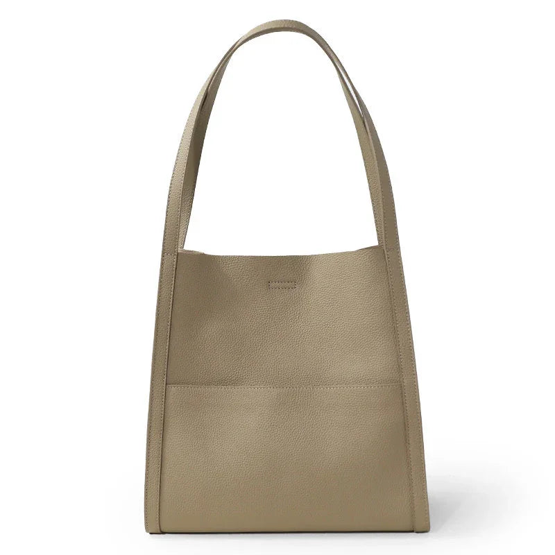 Beige grain cowhide leather tote bag with shoulder straps, minimalist design, front pocket.