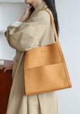 Minimalist tan leather tote bag with grain cowhide texture on woman's shoulder
