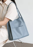 Woman holding a light blue grain cowhide leather tote bag with minimalist design