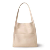 Minimalist beige cowhide leather tote bag with shoulder straps and front pocket on white background