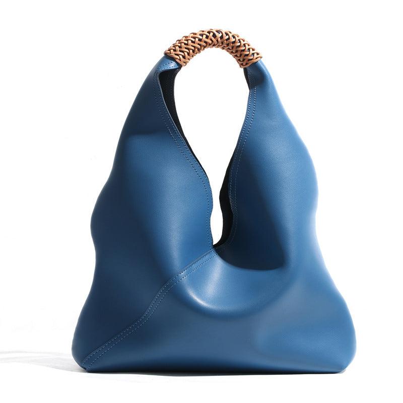 Blue genuine leather minimalist bucket bag with woven tan handle on white background