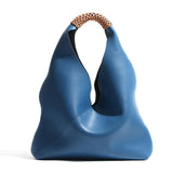 Blue genuine leather minimalist bucket bag with woven tan handle on white background