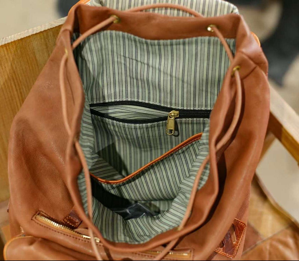 Interior view of a brown cowhide leather backpack with striped fabric lining and zip pocket
