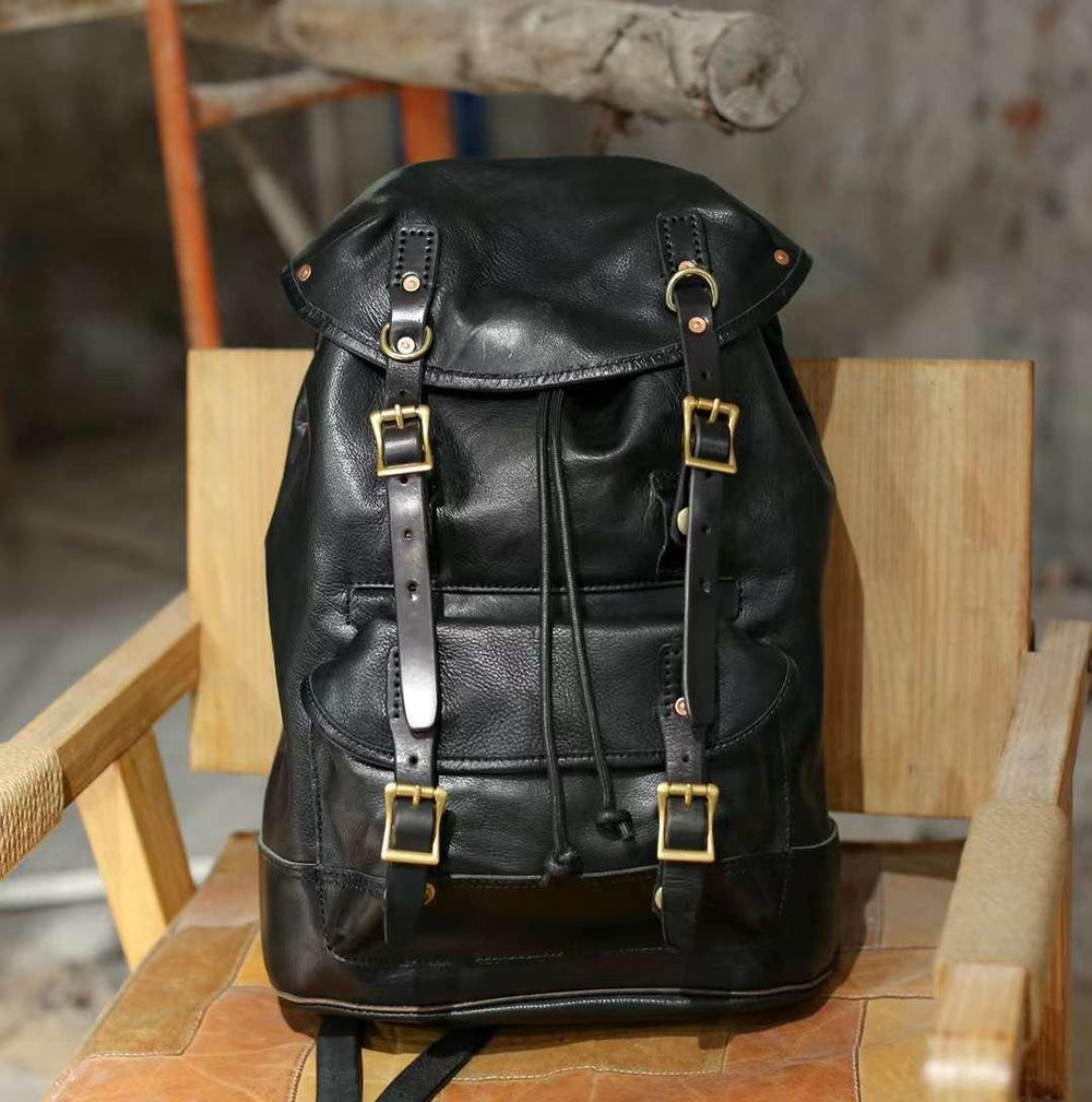 Men's black cowhide leather backpack with buckles, military style travel bag on a chair