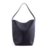 Minimalist black leather bucket bag with single shoulder strap on white background