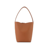 Minimalist tan leather bucket bag with single shoulder strap on white background