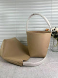 Minimalist tan leather bucket bag and large tote bag with textured finish, displayed indoors