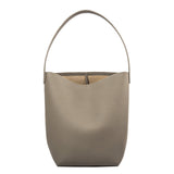 Minimalist large tan leather bucket bag with single shoulder strap on white background