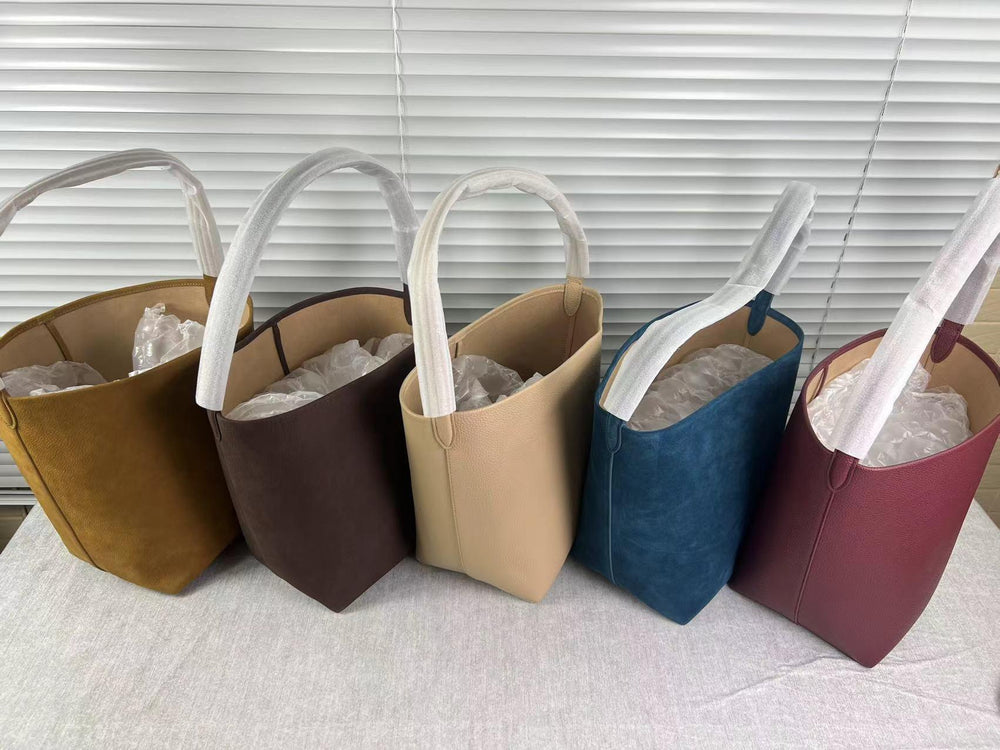 Assorted minimalist leather tote bags in tan, brown, beige, blue, and burgundy on display