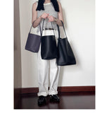 Woman in striped top holding three minimalist leather bucket bags in black and dark purple