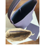Minimalist purple leather bucket bag with wide strap and beige zippered pouch insert