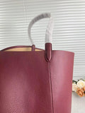 Close-up of a large tan pebbled leather bucket bag with shoulder strap, minimalist style