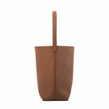 Minimalist tan leather bucket bag with single shoulder strap on plain white background