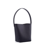 Minimalist black leather bucket bag with a single top handle on a white background