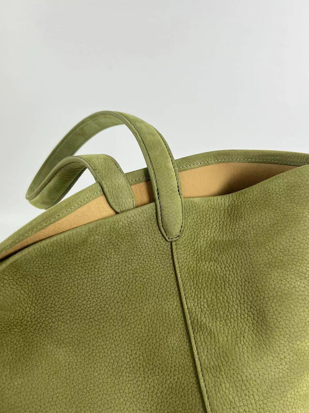 Close-up of an olive green leather bucket bag with textured finish and double handles
