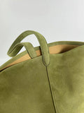 Close-up of an olive green leather bucket bag with textured finish and double handles