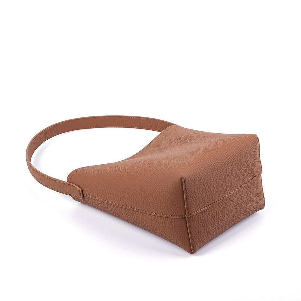 Tan minimalist leather bucket bag with wide shoulder strap on white background