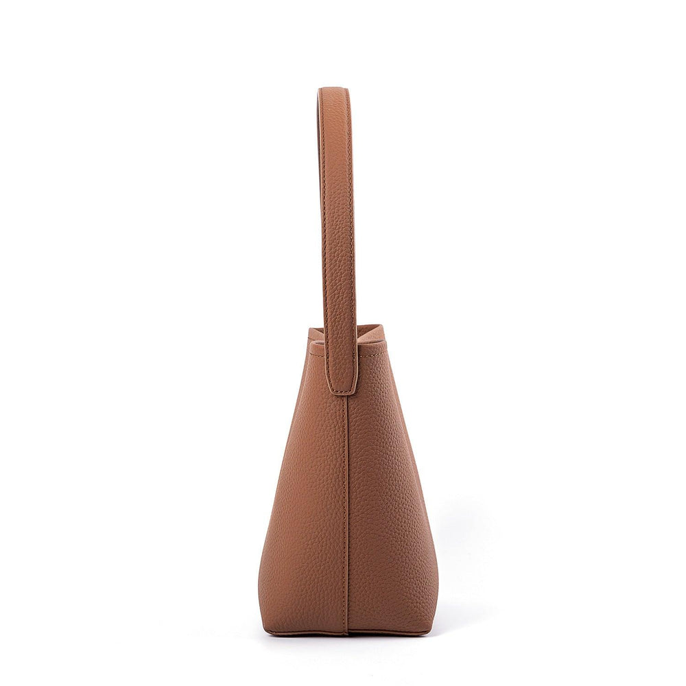 Side view of minimalist tan leather bucket bag with pebbled texture and shoulder strap