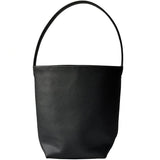 Minimalist black leather bucket bag with single shoulder strap on white background