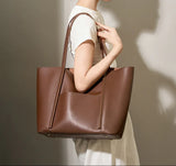 Woman carrying large brown minimalist genuine leather tote handbag with top handles