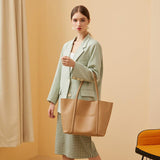 Woman carrying large beige genuine leather tote handbag with top handles in a minimalist room